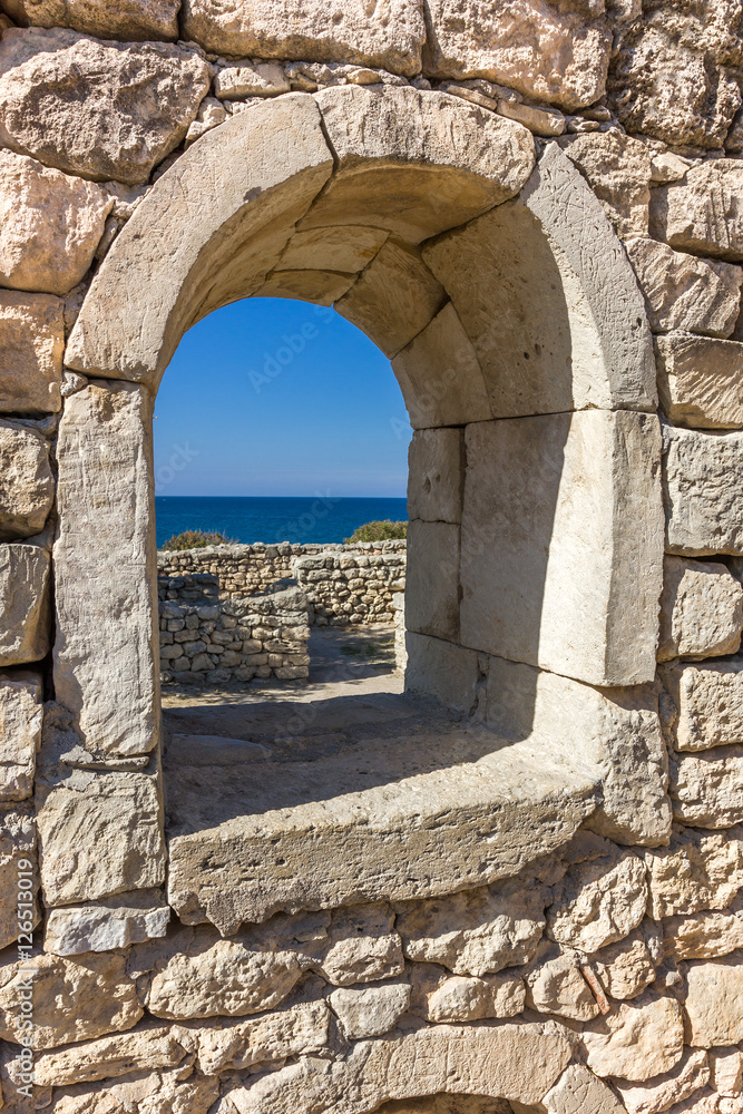 ancient stone wall with a semicircular window and a view of the