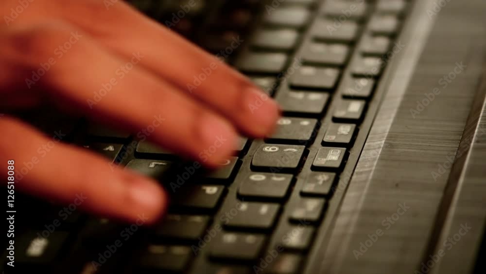 Close-up of a hand typing on a laptop keyboard