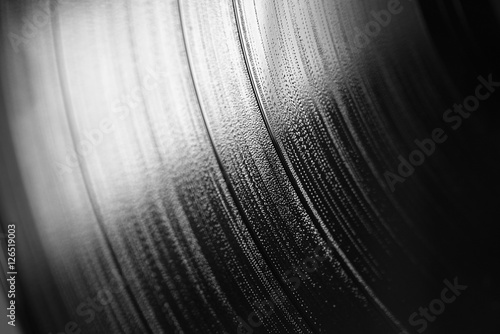 Macro di fianco di un disco musicale in vinile in bianco e nero con un riflesso di luce bianca in alto