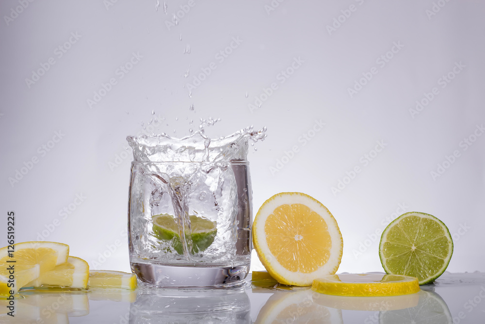 Splashes of water, lemon lime falling into a glass, isolated, reflection, white background, water drop Splashes of water, lemon lime falling into a glass, isolated, reflection, white background, water drop
