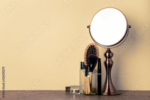 vintage metal mirror and make up set on the wooden table.