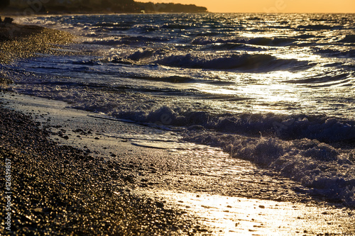 sunset on the beach with black sand. Aegean sea, pebble photo