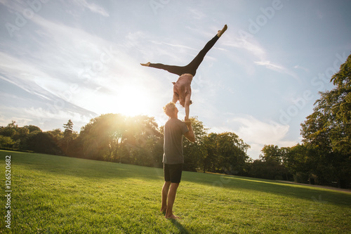 Fit young couple doing acro yoga in park