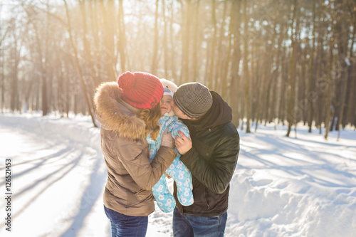 happy young family with their baby son spending time outdoor in the winter park