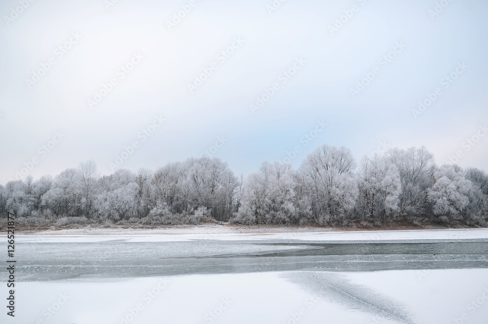 Winter landscape of snow-covered fields, trees and river