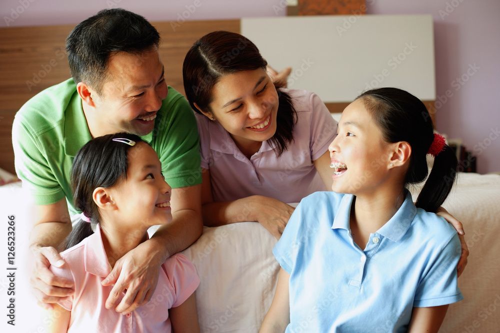 Father and mother with two daughters in bedroom Father and mother with two daughters in bedroom