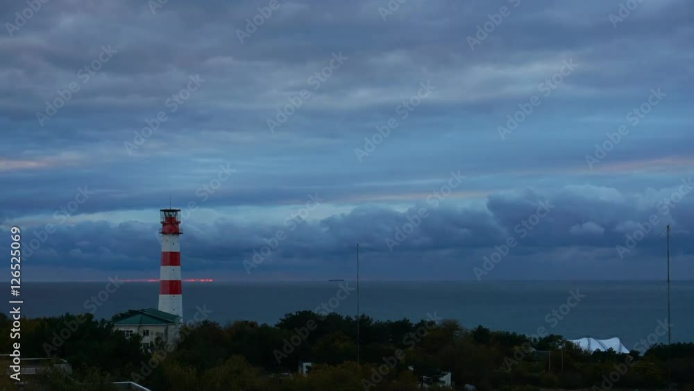 Cargo ship passes by a beautiful majestic lighthouse Cargo ship passes by a beautiful majestic lighthouse
