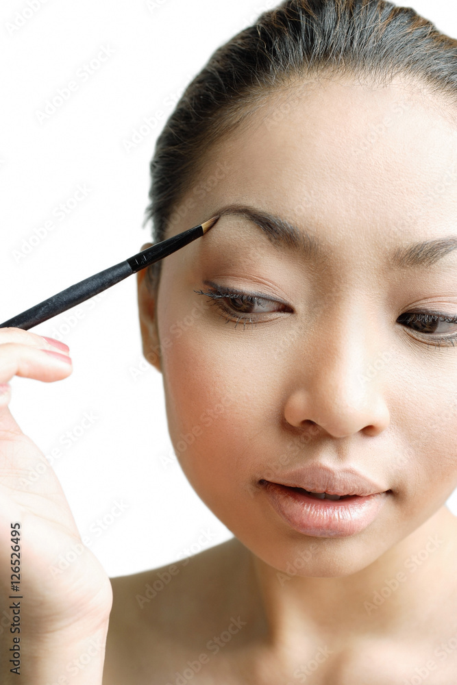 Young woman holding eyebrow pencil to eyebrow Young woman holding eyebrow pencil to eyebrow