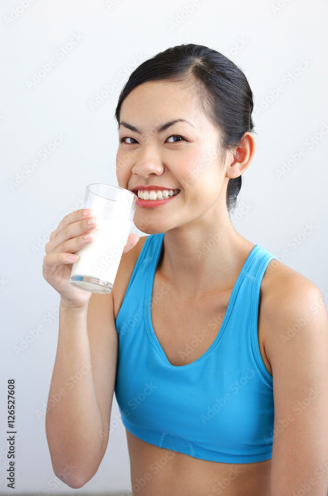 Woman drinking glass of milk, smiling at camera Woman drinking glass of milk, smiling at camera