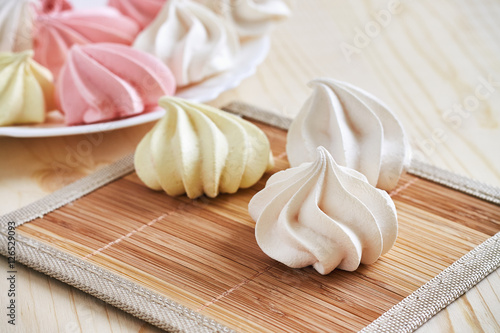 Fresh delicious colored meringue cookies on wooden table