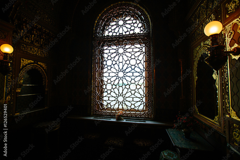 The interior in the Moorish style, dim lights. Window with tracery lattice