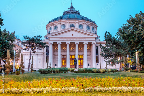 Romanian Atheneum at sunset with red and yellow flowers in front.Blue sky. Bucharest, Romania.
