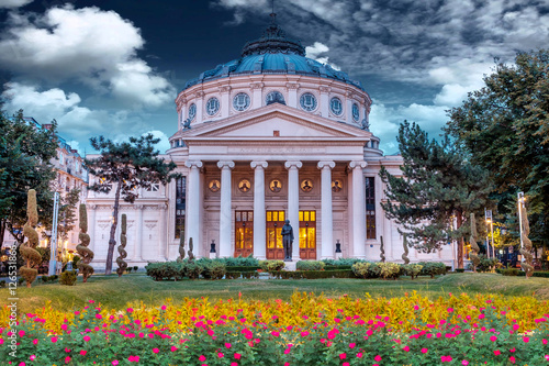 Romanian Atheneum at sunset with red and yellow flowers in front.Blue sky. Bucharest, Romania. photo