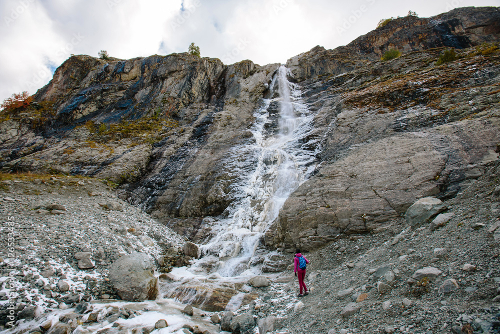 Sofia waterfalls in the mountains of the Caucasus. Russia, Karachay-Cherkess Republic, near the settlement of Arkhyz. Girl tourist on background of high falls
