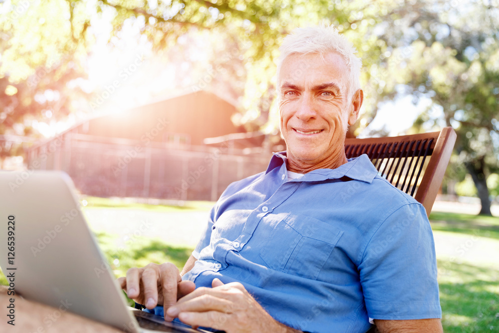 Senior man with notebook sitting in the park Senior man with notebook sitting in the park