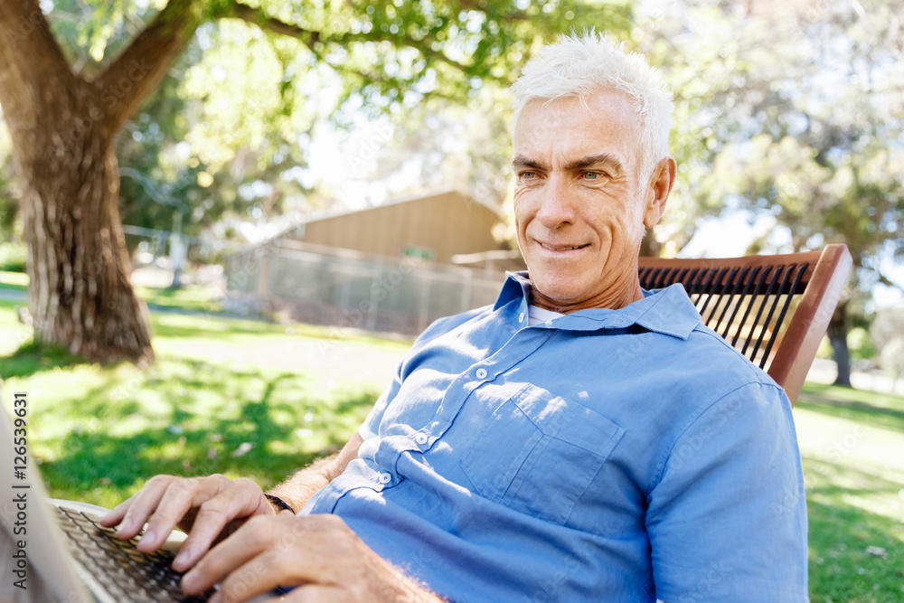 Senior man with notebook sitting in the park Senior man with notebook sitting in the park