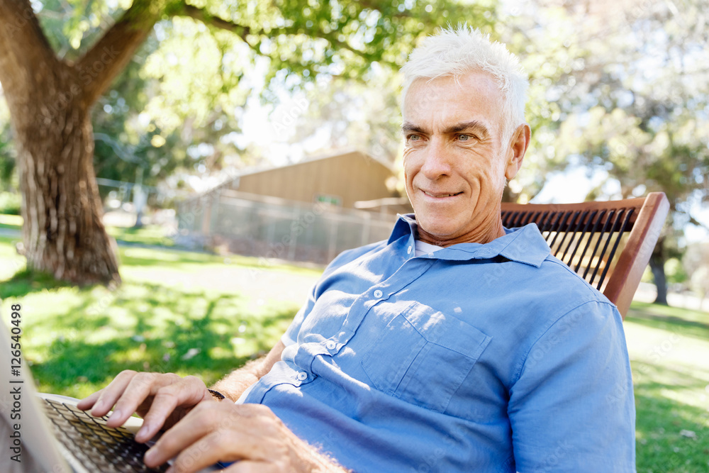 Senior man with notebook sitting in the park Senior man with notebook sitting in the park
