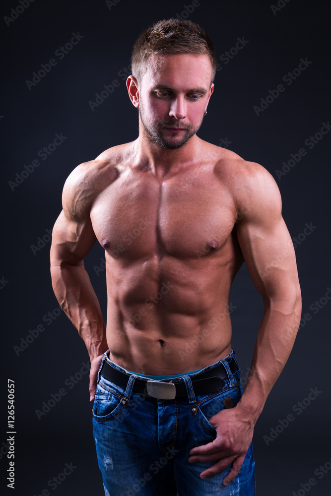 portrait of young muscular man posing over dark background portrait of young muscular man posing over dark background