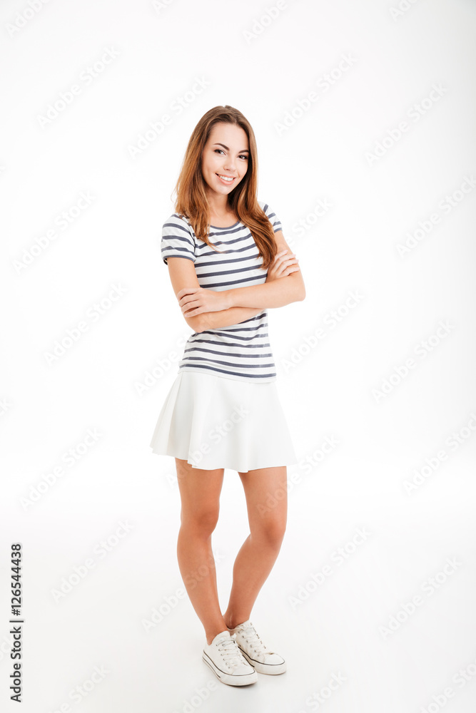 Full length of cheerful young woman standing with arms folded Full length of cheerful young woman standing with arms folded