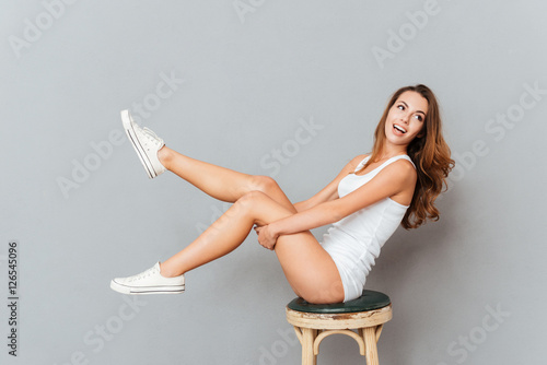 Fotótapéta Laughing woman sitting on the chair with raised legs