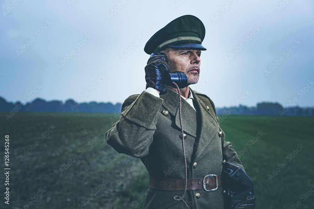 Vintage 1940s military officer calling with field phone while st
