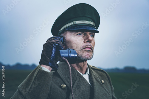 Vintage 1940s military officer calling with field phone while st © ysbrandcosijn
