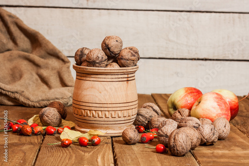 Apples and walnat in bascet,briar on old wooden board with autumn leaves country decoration photo