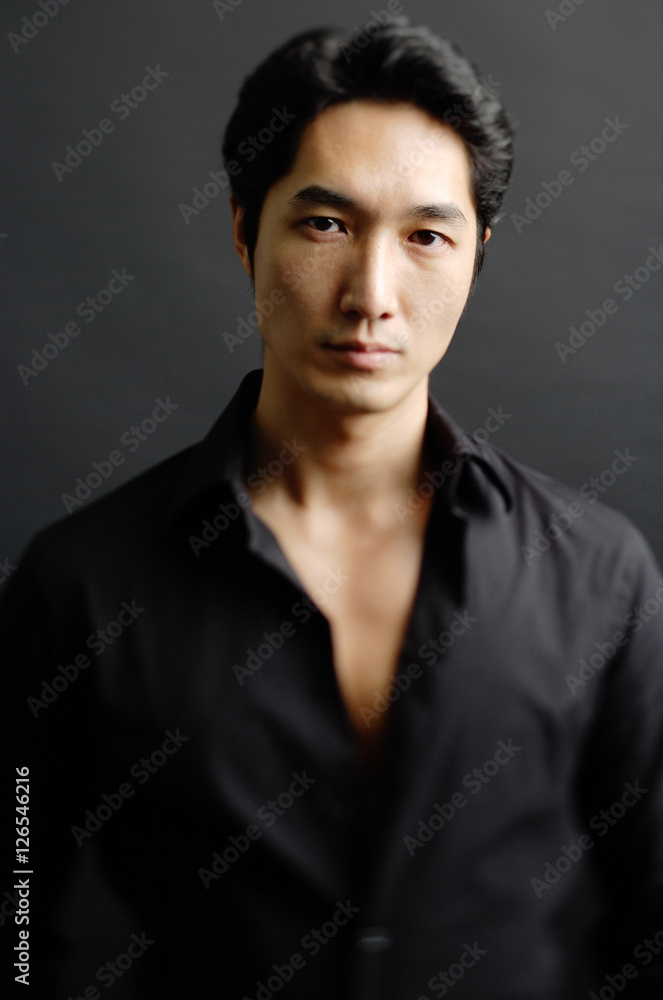 Man in black shirt, standing against black background