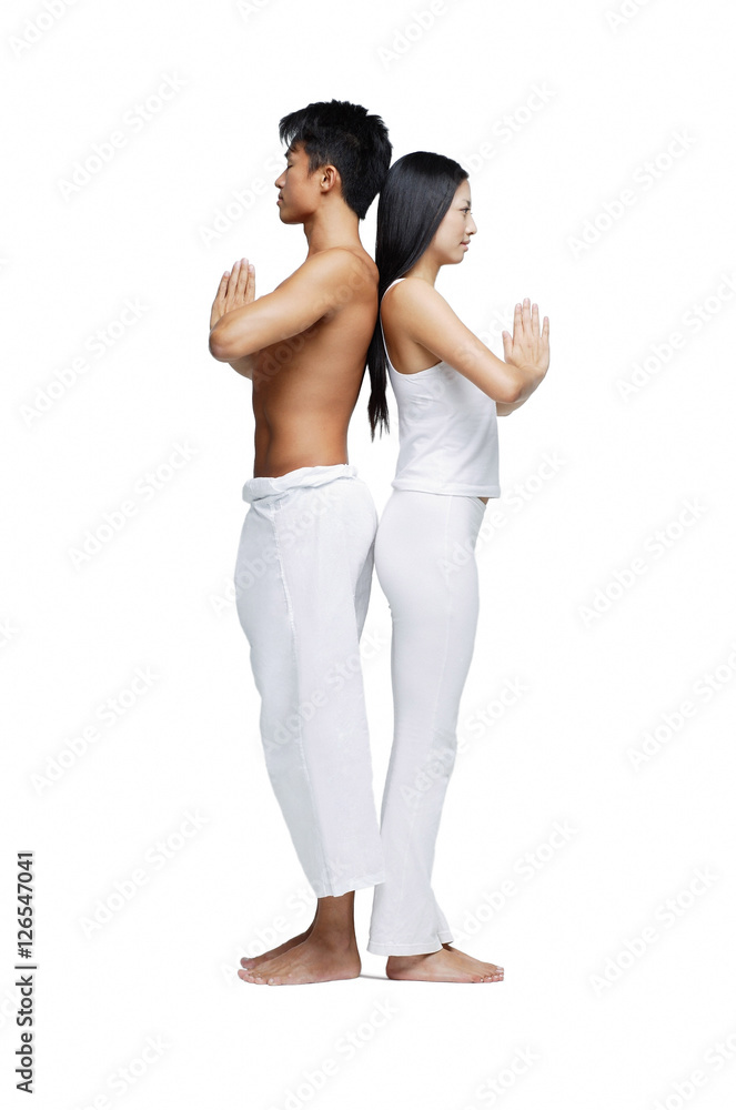 Obraz premium Couple doing yoga position, standing back to back