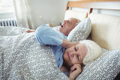 Photography Man snoring and woman covering her ears while sleeping on bed