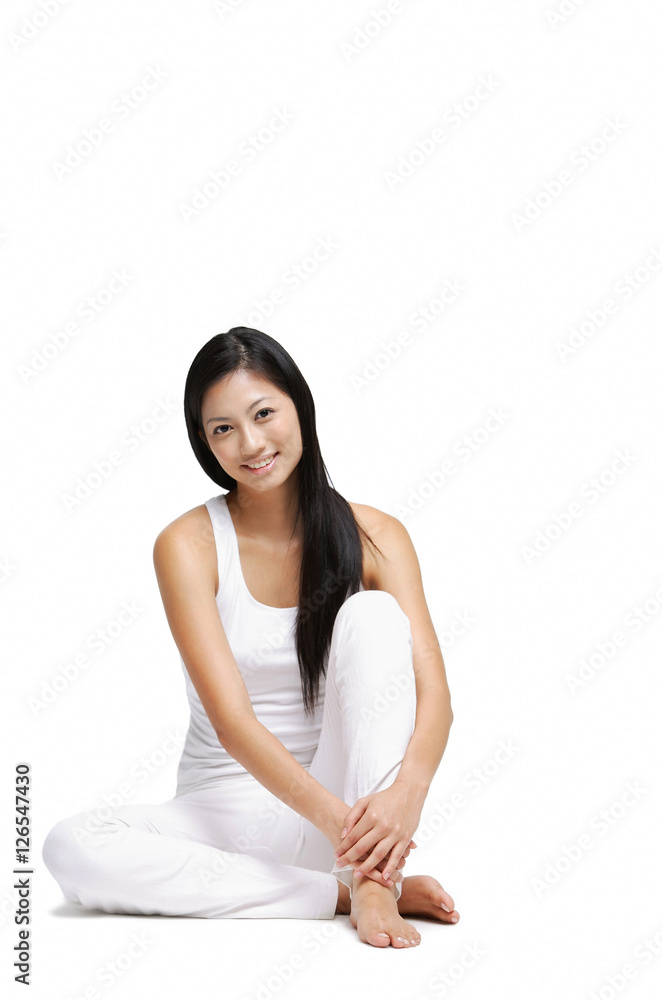 Woman sitting on floor, hugging knee, looking at camera Woman sitting on floor, hugging knee, looking at camera