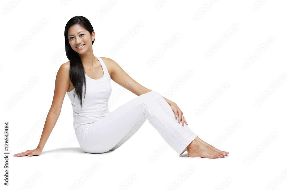 Woman sitting on floor, looking at camera, legs outstretched