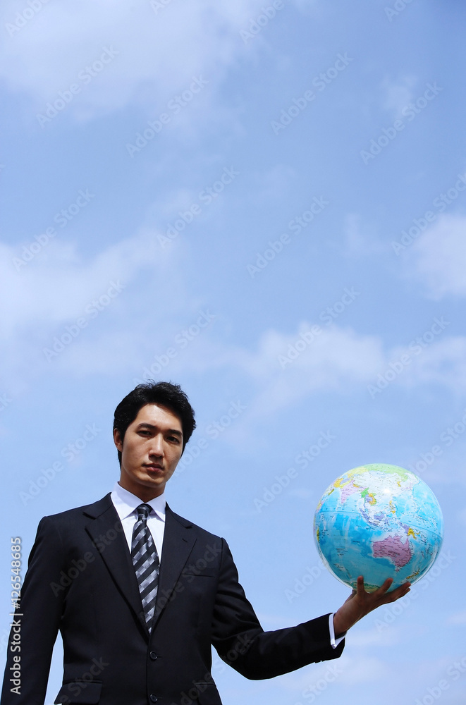 Businessman holding globe, looking at camera Businessman holding globe, looking at camera