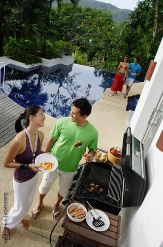 Couple grilling food over barbeque