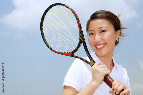 Young woman holding tennis racket, smiling at camera © Alexander