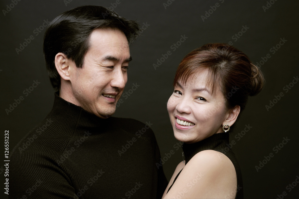 Couple together, woman smiling at camera, man watching her Couple together, woman smiling at camera, man watching her