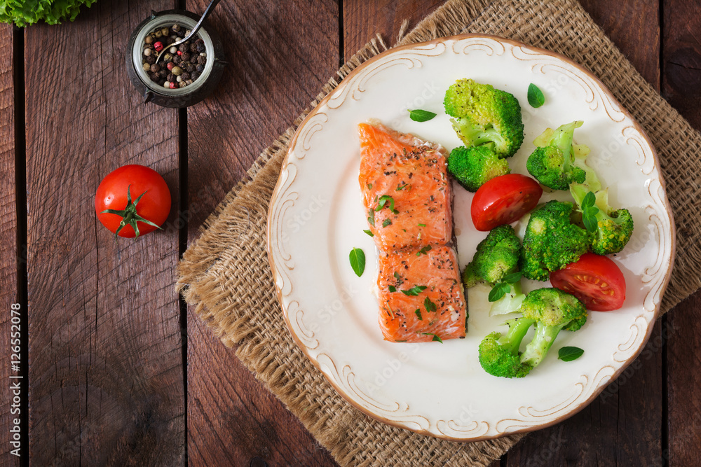 Baked fish salmon garnished with broccoli and tomato. Dietary menu. Fish menu. Seafood - salmon. Top view Baked fish salmon garnished with broccoli and tomato. Dietary menu. Fish menu. Seafood - salmon. Top view