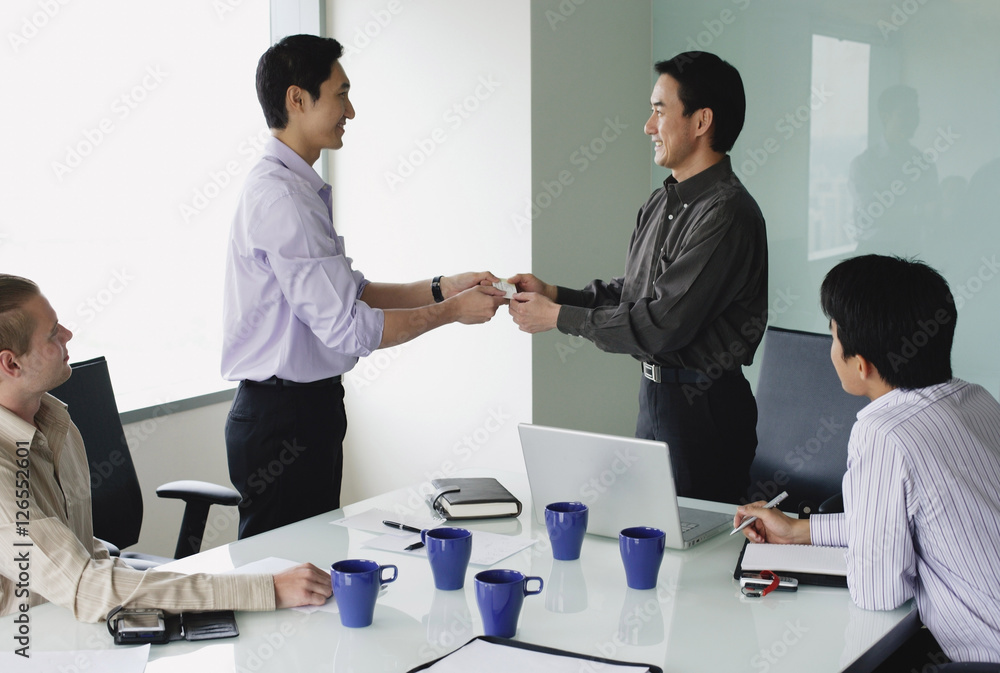 Executives in meeting room, exchanging business cards
