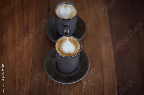 Hot latte art with black glass on wooden table