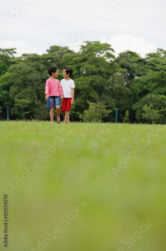 Two girls on grass  walking  holding hands