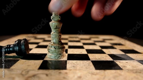 A white chess figure king overthrows a black king from the chess board and takes his place.... photo