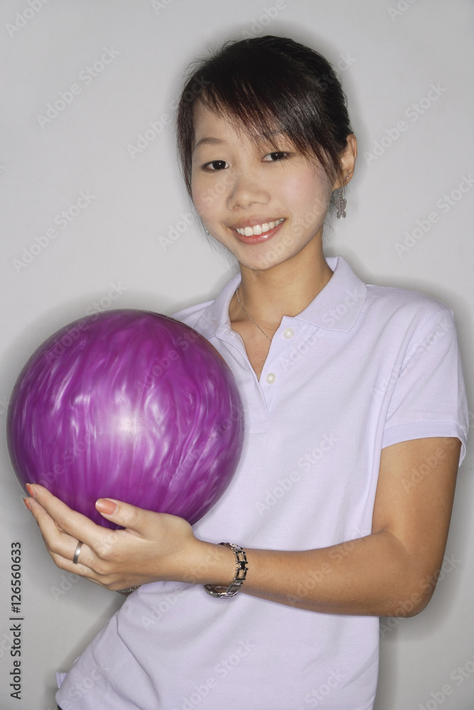 Woman holding purple bowling ball, smiling at camera Woman holding purple bowling ball, smiling at camera