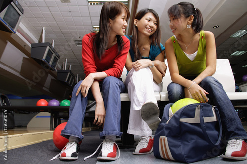 Women sitting side by side in bowling alley