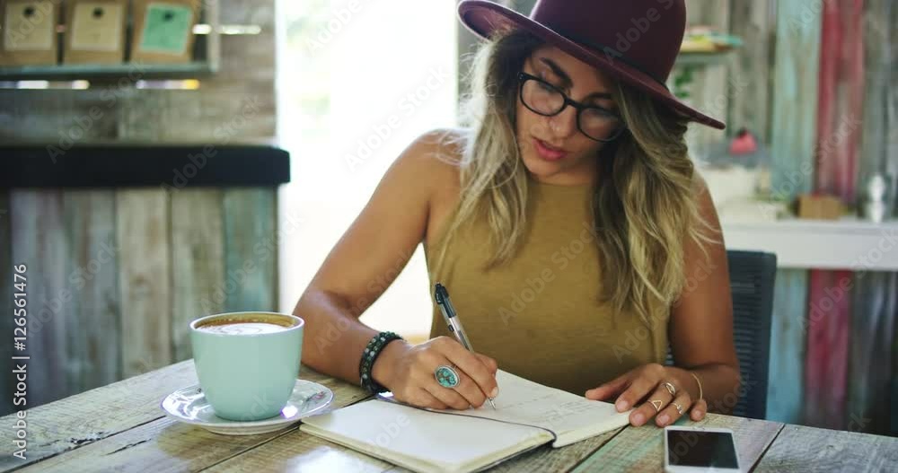 Woman writing in journal in cafe, working in mobile office