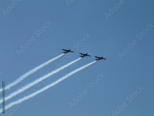4 small propeller plane in aerobatic display with smoke trails behind them