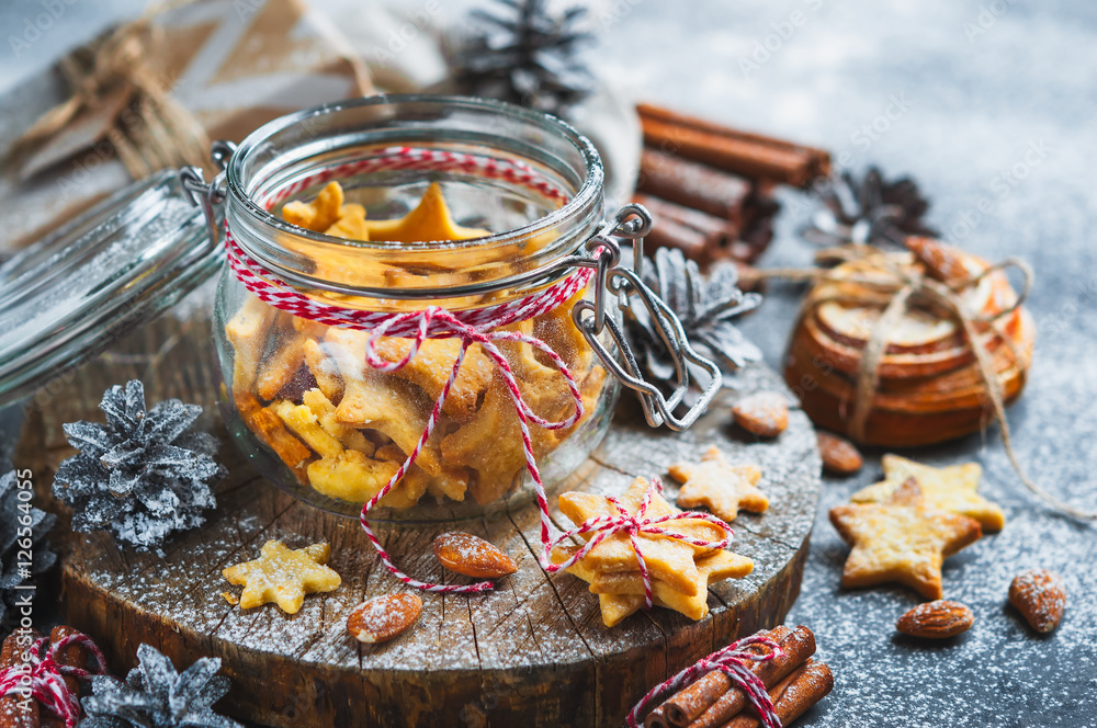 Glass jar with ginger Christmas cookies in the form of stars,cinnamon sticks,nuts Glass jar with ginger Christmas cookies in the form of stars,cinnamon sticks,nuts