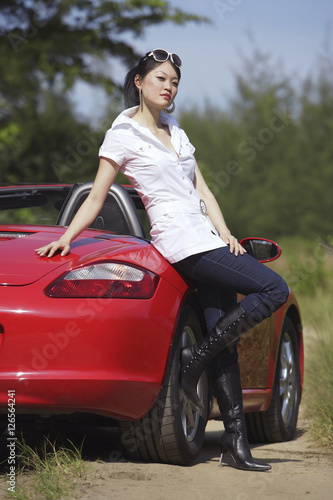 Woman leaning on red sports car