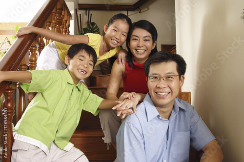 Family with two children, sitting on stairs, smiling at camera, portrait