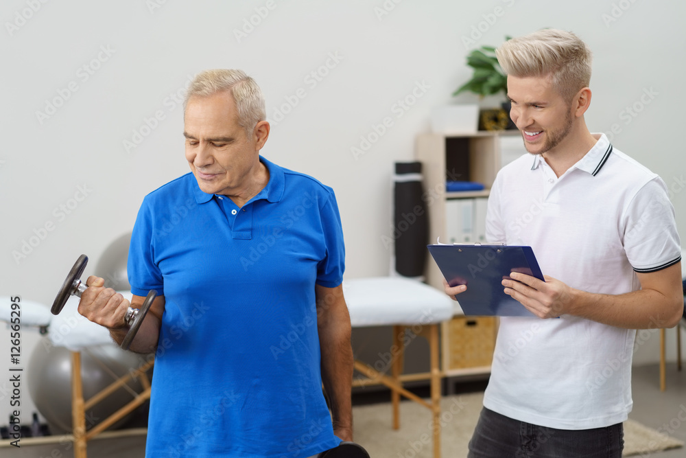 Obraz premium senior trainiert mit hanteln mit einem physiotherapeut