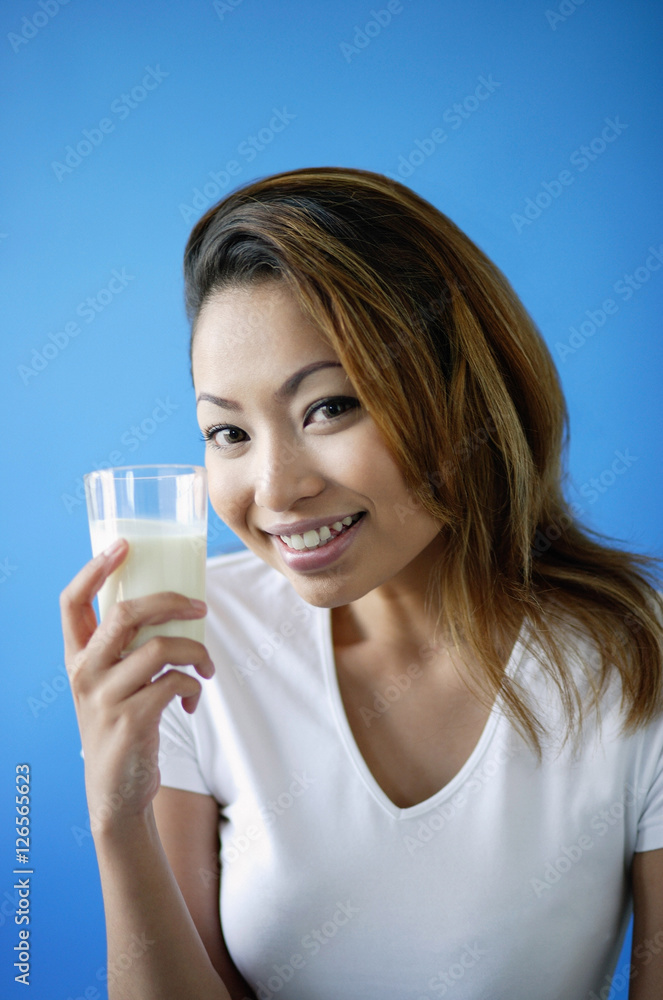 Woman holding a glass of milk, smiling at camera Woman holding a glass of milk, smiling at camera